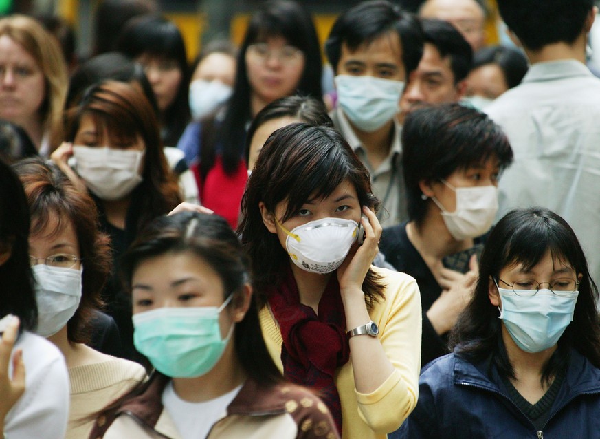 HONG KONG - APRIL 1: People wear surgical masks to try to reduce the chance of infection from SARS (Severe Acute Respiratory Syndrome)whilst walking through the business district April 1, 2003 in Hong ...