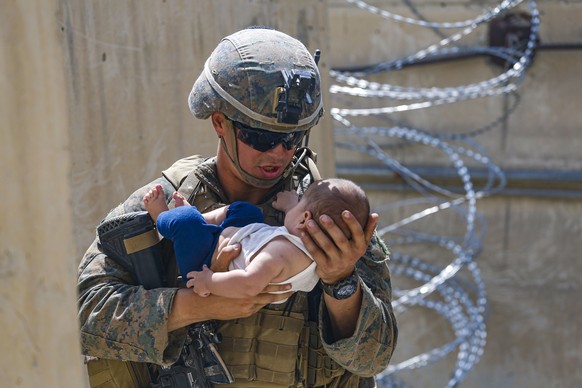 Ein US-amerikanischer Soldat des Marine Corps tröstet am Flughafen von Kabul einen Säugling, während er auf dessen Mutter wartet.
