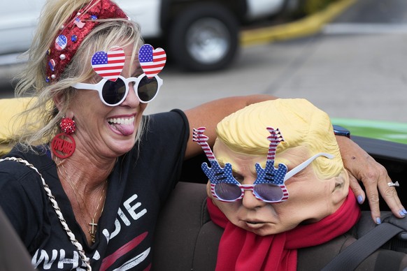 Michelle Lilly, a supporter of former President Donald Trump, poses with a mask of the former president as she attends a rally, Tuesday, April 4, 2023, in West Palm Beach, Fla., Supporters hoped to ca ...
