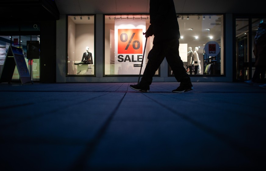 Ein Mann mit Stock geht in der Innenstadt an einem Schaufenster vorbei, in dem ein Schild mit der Aufschrift &quot;Sale&quot; zu sehen ist. Aufgrund der anhaltend hohen Corona-Infektionszahlen wird de ...