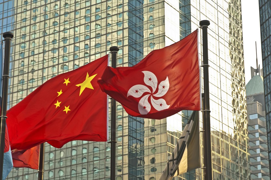 Die Flaggen von China und Hongkong wehen vor einem Bürogebäude in Hongkong.