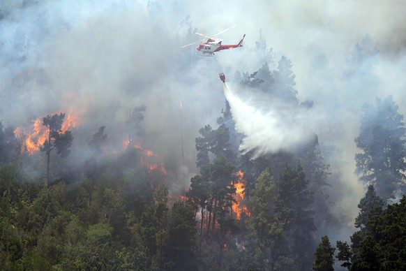 dpatopbilder - 23.07.2022, Spanien, Santa Cruz de Tenerife: Ein L�schhubschrauber sch�ttet Wasser auf einen Waldbrand. Die verbrannte Fl�che betr�gt bereits mehr als 2 000 Hektar und der Windwechsel e ...