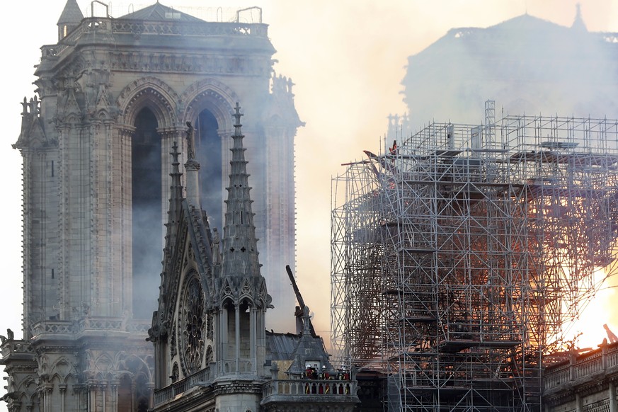 Firefighters tackle the blaze as flames and smoke rise from Notre Dame cathedral as it burns in Paris, Monday, April 15, 2019. Massive plumes of yellow brown smoke is filling the air above Notre Dame ...
