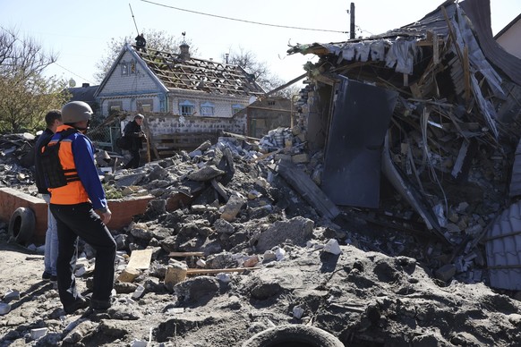 03.05.2023, Ukraine, Saporischschja: Menschen betrachten ein durch Beschuss zerstörtes Gebäude. Foto: Andriyenko Andriy/AP/dpa +++ dpa-Bildfunk +++