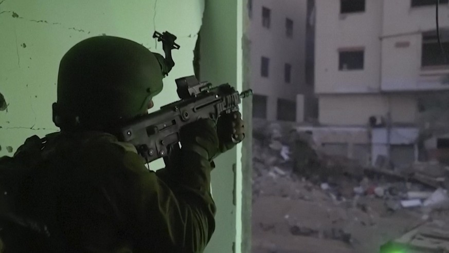 HANDOUT - 15.11.2023, Palästinensische Gebiete, Gaza: In diesem Bild aus einem von den israelischen Verteidigungskräften am 14. November 2023 veröffentlichten Video hält ein israelischer Soldat eine W ...