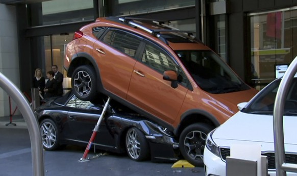 In this image made from video, a Porsche Carrera car is underneath another car in Sydney, Australia Thursday, May 31, 2018. Australian media say a valet drove the soft-top Porsche Carrera under anothe ...