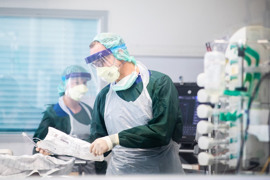 01.04.2020, Nordrhein-Westfalen, Essen: Krankenpfleger arbeiten in Schutzkleidung in einem Krankenzimmer auf der Intensivstation des Uniklinikums Essen, in dem ein Corona-Patient aus Frankreich behand ...