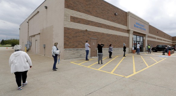 Voters wait in line to enter the Medina County Board of Elections to cast their vote for the Ohio primary election while observing social-distancing during to the Coronavirus pandemic in Medina, Ohio  ...
