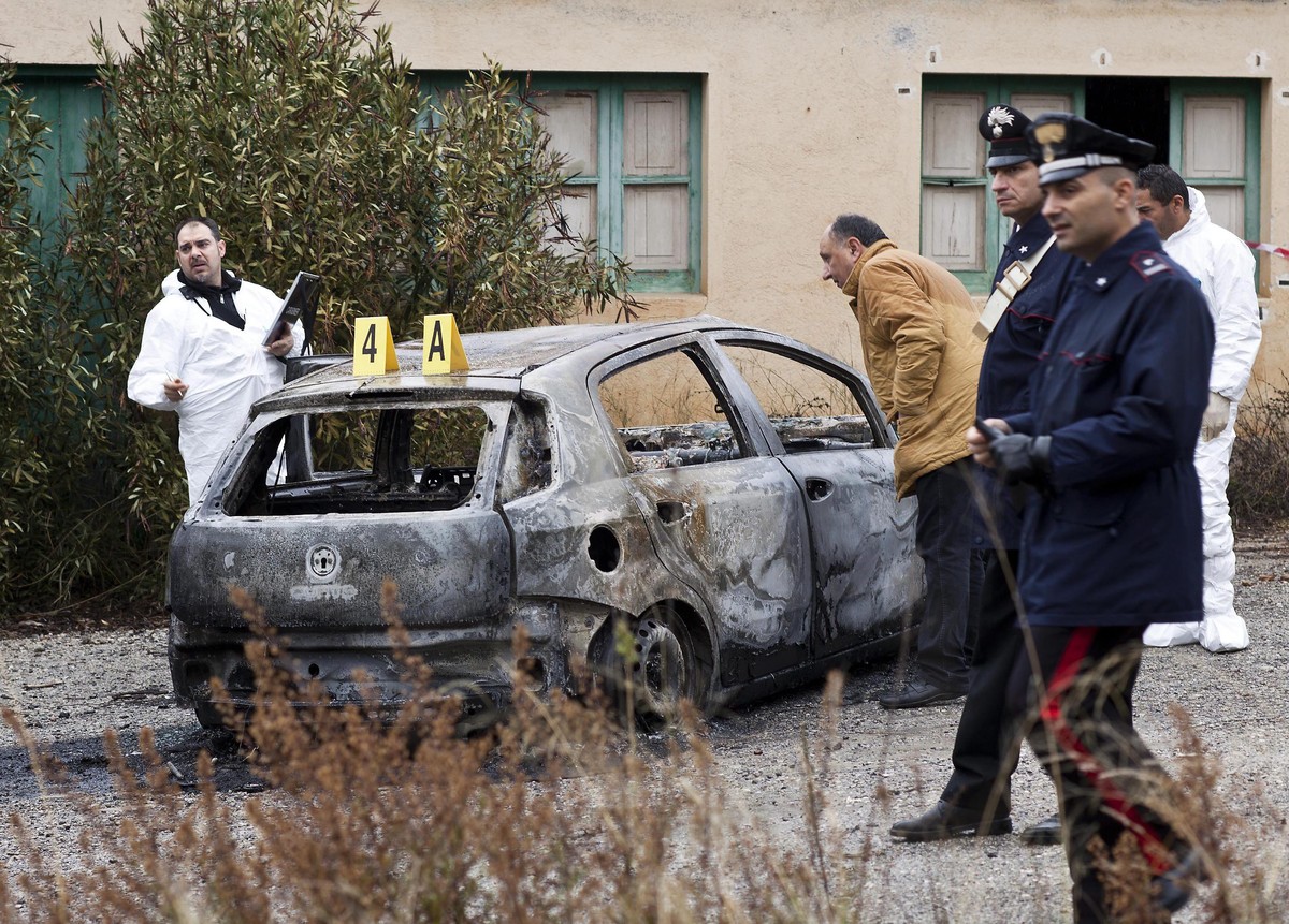 ARCHIV - 19.01.2014, Italien, Cassano Allo Ionio: Ermittler arbeiten an einem verbrannten Auto, in dem drei verbrannte Leichen in Cassano allo Ionio, Provinz Kalabrien, S