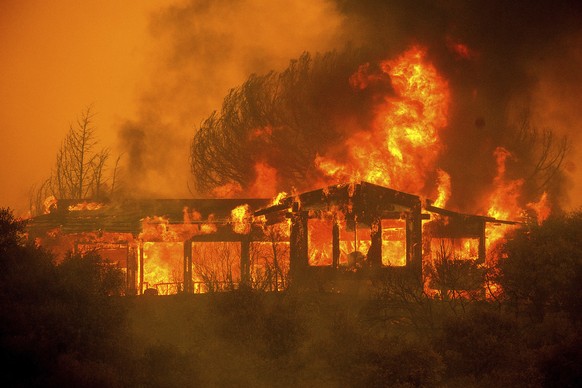 FILE - In this Monday, July 30, 2018, file photo, a home burns as the River Fire rages near Finley, Calif. Authorities say a rapidly expanding Northern California wildfire burning over an area the siz ...