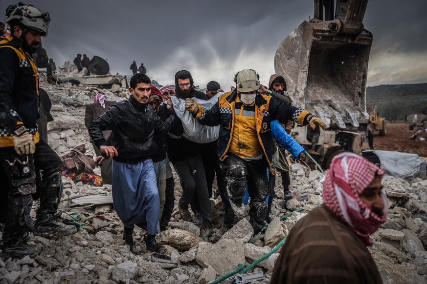 06.02.2023, Syrien, Harem: Zivilisten und Mitglieder des syrischen Zivilschutzes führen Such- und Rettungsmaßnahmesuchen in den Trümmern eines zerstörten Gebäudes durch. In der Türkei und in Syrien si ...