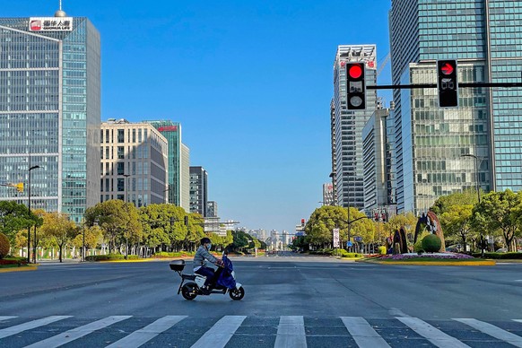 SHANGHAI, CHINA - APRIL 9, 2022 - A food delivery rider passes an empty intersection in Pudong, Shanghai, China, On April 9, 2022. Shanghai is under lockdown.
