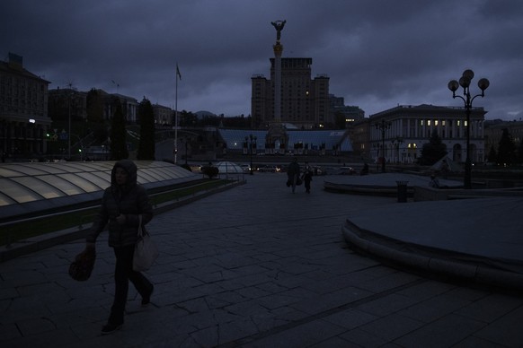 People walk in Independence Square at twilight in Kyiv, Ukraine, Monday, Oct. 31, 2022. Rolling blackouts are increasing across Ukraine as the government rushes to stabilise the energy grid and repair ...