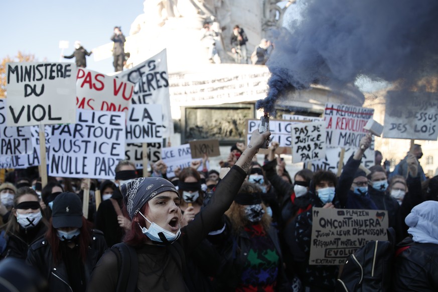 Ein Demonstrant hält während eines Protestes in Paris gegen ein neues Sicherheitsgesetz ein bengalisches Feuer in die Höhe.