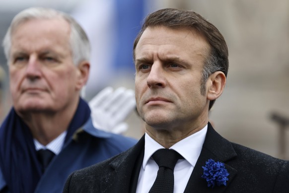 FILE - French President Emmanuel Macron, right, and Prime Minister Michel Barnier stand at attention during commemorations marking the 106th anniversary of the November 11, 1918, Armistice, ending Wor ...