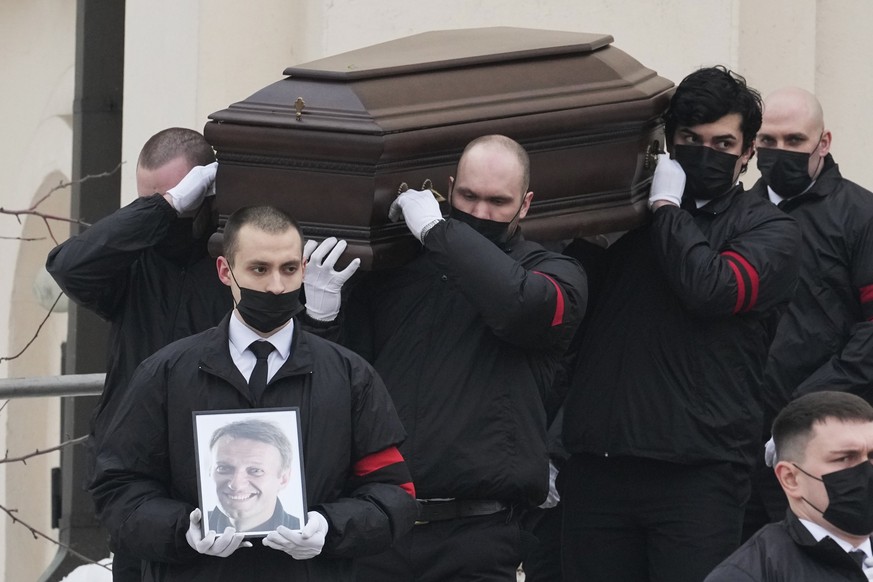 dpatopbilder - 01.03.2024, Russland, Moskau: Männer tragen den Sarg und ein Porträt des russischen Oppositionsführers Alexej Nawalny aus der Kirche zu Ehren der Gottesmutterikone «Lindere meine Trauer ...