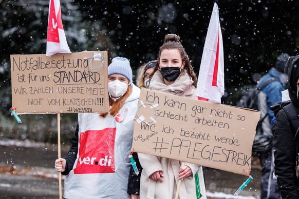 Zwei Pflegekräfte aus der Kardiologie des Klinikums Großhadern der Ludwig-Maximilians-Universität München halten während einer Demonstration der Klinikbeschäftigten vor dem Innenstadtklinikum ihre Sch ...