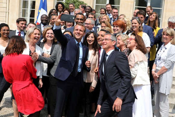 French President Emmanuel Macron (C) takes a selfie with La Republique en Marche (LREM) party members of Parliament after the presentation of the French government&#039;s urban policy aimed at the cou ...