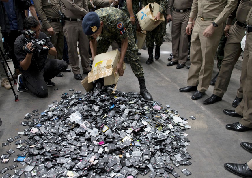 A Thai law-enforcement officer unloads a box full of mobile batteries during a raid at a factory accused of importing and processing electronic waste in the suburbs of Bangkok, Thailand on Thursday, J ...