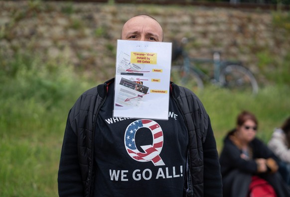 23.05.2020, Hessen, Frankfurt/Main: Bei einer Demonstration gegen die Corona-Maßnahmen der Regierung steht ein Mann mit einem vor dem Mundschutz gehefteten Plakat, auf dem er versucht zu beweisen, das ...