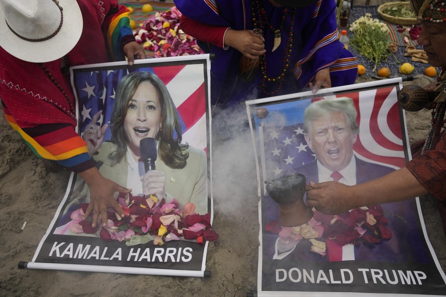 Shamans perform a good luck ritual holding posters of Democratic presidential nominee Vice President Kamala Harris and Republican presidential nominee former President Donald Trump, at the beach in Li ...