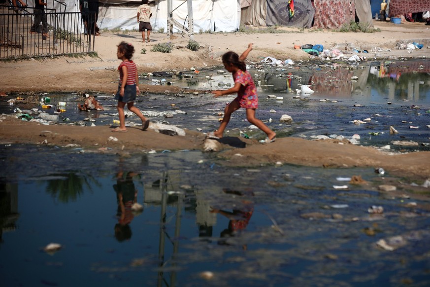 Hamas Israel Conflict Palestinian children are walking past a pool of sewage water on a street in Deir el-Balah in the central Gaza Strip on July 23, 2024, as municipal infrastructures are failing due ...