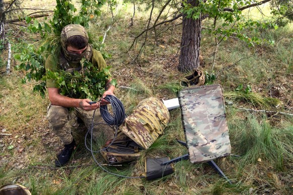 A Ukrainian soldier of the 61st Separate Mechanized Brigade uses the Starlink system during military exercises in the Chernihiv region, Ukraine, June 2023 (Photo by Maxym Marusenko/NurPhoto via Getty  ...