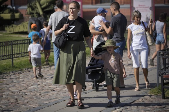 FILE - A woman and her child wearing t-shirts with letter Z, which has become a symbol of the Russian military walk in the Artillery museum in St. Petersburg, Russia, Saturday, Aug. 20, 2022. Six mont ...