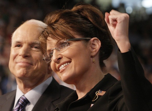 FILE - Republican presidential nominee Sen. John McCain, left, smiles as his Vice Presidential running mate, Alaska Gov. Sarah Palin, pumps her fist as she is introduced to supporters at a campaign ra ...