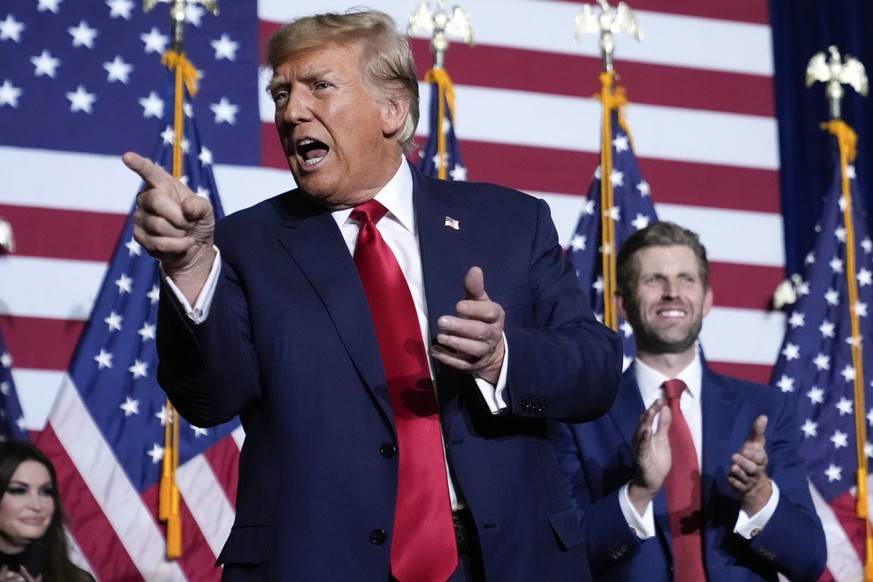 Republican presidential candidate former President Donald Trump points to the crowd, accompanied by his son, Eric, at a caucus night party in Des Moines, Iowa, Monday, Jan. 15, 2024. (AP Photo/Andrew  ...