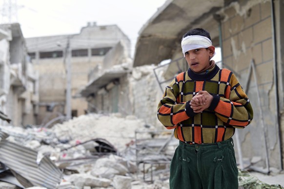 Das am 25.02.2014 veröffentlichte Foto zeigt einen verletzten Jungen, der nach einem Fassbombenangriff in Aleppo (Syrien) am Vortag vor dem zerstörten Haus seiner Familie im Stadtteil Sakhour steht.