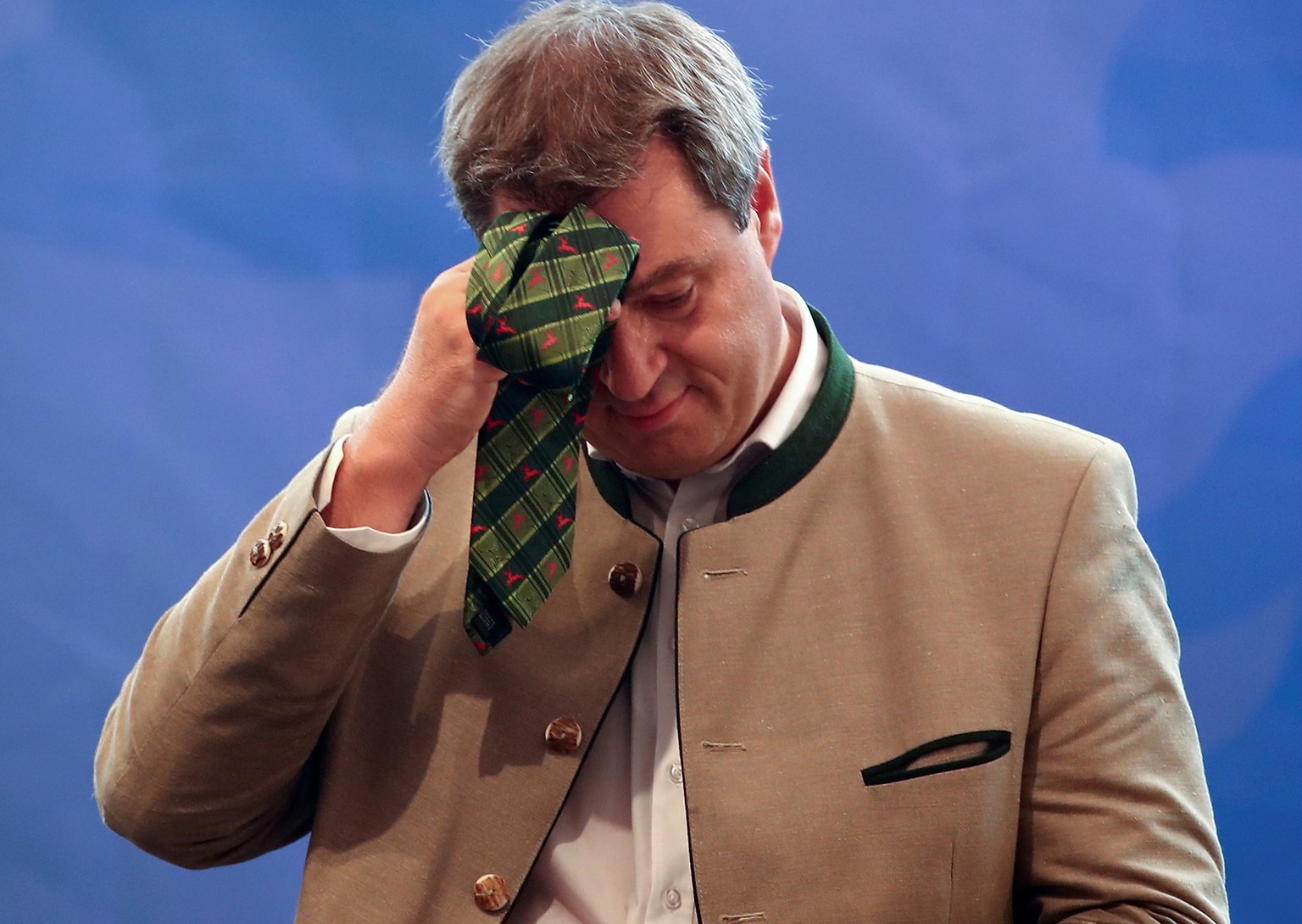 Bavarian State Prime Minister Markus Soeder of the Christian Social Union (CSU) wipes of the sweat with his tie as he delivers a speech at an election rally at one of Bavaria's oldest fairs, the Gilla ...