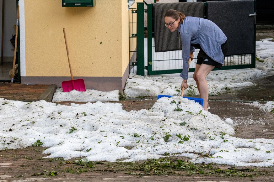 dpatopbilder - 20.06.2022, Bayern, Wang: Eine Frau schaufelt Hagelkörner nach einem schweren Unwetter in Landkreis Freising. Bei dem Unwetter ist nach Angaben des Landratsamtes Freising ein Mensch ums ...