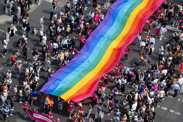 ARCHIV - 22.07.2023, Berlin: Menschen ziehen auf der 45. Berlin Pride-Parade zum Christopher Street Day (CSD) mit einer überdimensionalen Regenbogenfahne durch die Stadt. Der Berliner CSD ist eine der ...