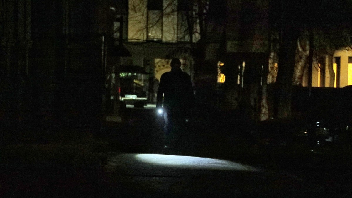 05.12.2022, Ukraine, Odessa: Ein Mann leuchtet sich den Weg mit einer Taschenlampe in einer dunklen Stra