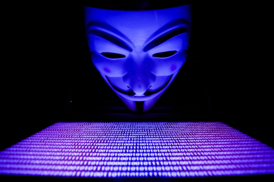 Binary code displayed on a laptop screen and Guy Fawkes mask are seen in this illustration photo taken in Krakow, Poland on March 1, 2022. Global hacker group Anonymous declared &#039;cyber war&#039;  ...