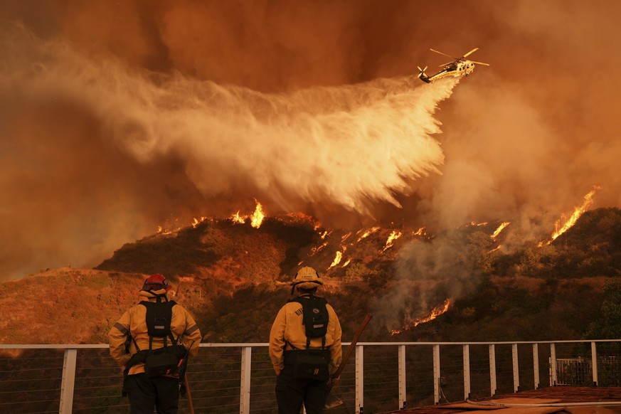 11.01.2025, USA, Los Angeles: Feuerwehrleute beobachten, wie Löschwasser auf das Palisades-Feuer im Mandeville Canyon Angeles geworfen wird. Foto: Jae C. Hong/AP/dpa +++ dpa-Bildfunk +++