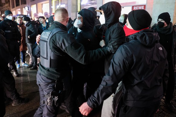 Ein Polizist hält eine Gruppe davon ab den Weg der Gegner der Corona-Maßnahmen zu blockieren. In der Leipziger Innenstadt finden Demonstrationen unter dem Motto «Gemeinsam für Demokratie und Solidarit ...