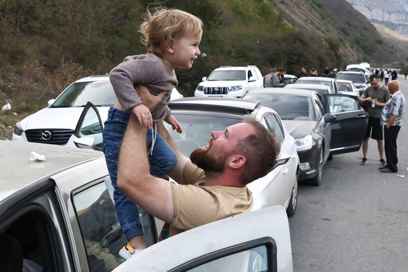 REPUBLIC OF NORTH OSSETIA-ALANIA, RUSSIA - SEPTEMBER 28, 2022: A man holds a child on the road for the Verkhny Lars checkpoint on the Russian-Georgian border. According to the Georgian Interior Minist ...