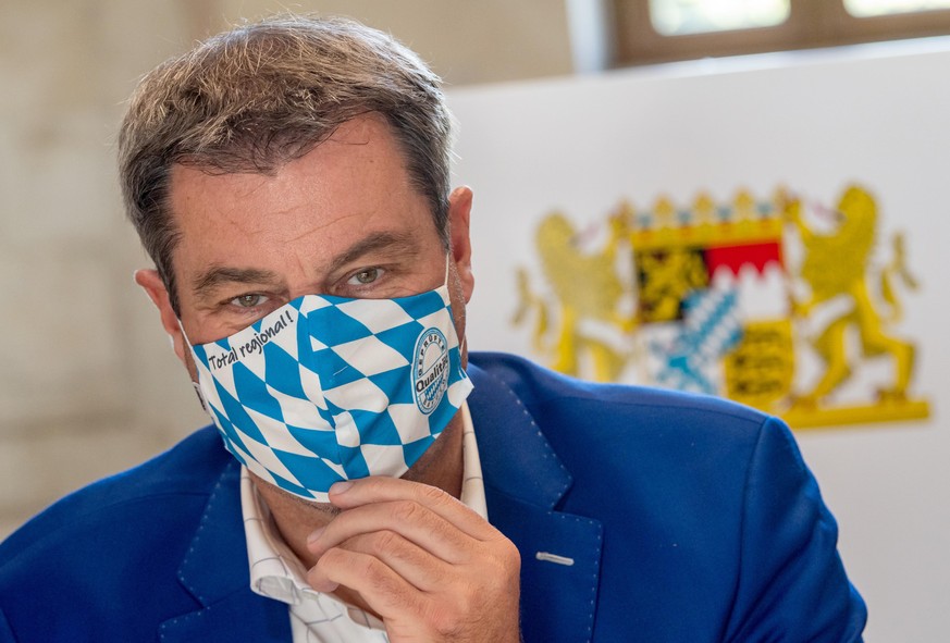 ARCHIV - 21.07.2020, Bayern, München: Markus Söder (CSU), Ministerpräsident von Bayern, trägt zu Beginn der Kabinettssitzung in der Bayerischen Staatskanzlei eine Mundschutzmaske im weiß-blauem Rauten ...