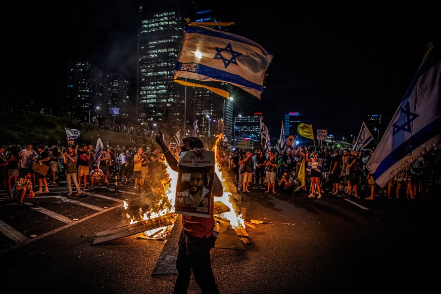 September 1, 2024, Tel Aviv, Israel: A protestor waves the Israeli flag near a bonfire along the Ayalon high way during the demonstration. Organizers claim that over 700,000 Israelis surged into the s ...