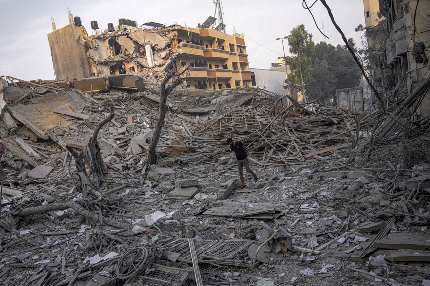 Palestinians inspect the rubble of a building after it was struck by an Israeli airstrike, in Gaza City, Sunday, Oct. 8, 2023. The militant Hamas rulers of the Gaza Strip carried out an unprecedented, ...