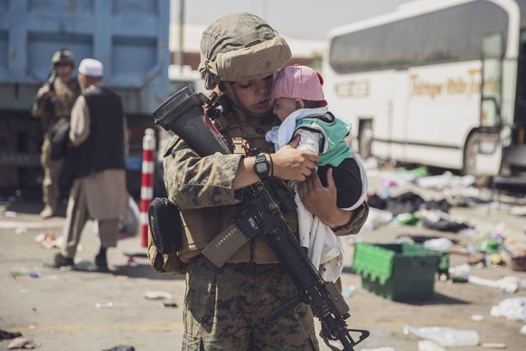 August 28, 2021 - Kabul, Afghanistan - A U.S. Marine with the 24th Marine Expeditionary Unit MEU carries a baby as the familiy processes through the Evacuation Control Center ECC during an evacuation  ...