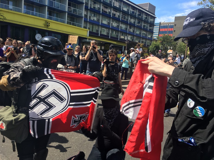 Counter protesters tear a Nazi flag, Saturday, Aug. 4, 2018 in Portland, Ore. Small scuffles broke out Saturday as police in Portland, Oregon, deployed &quot;flash bang&quot; devices and other means t ...