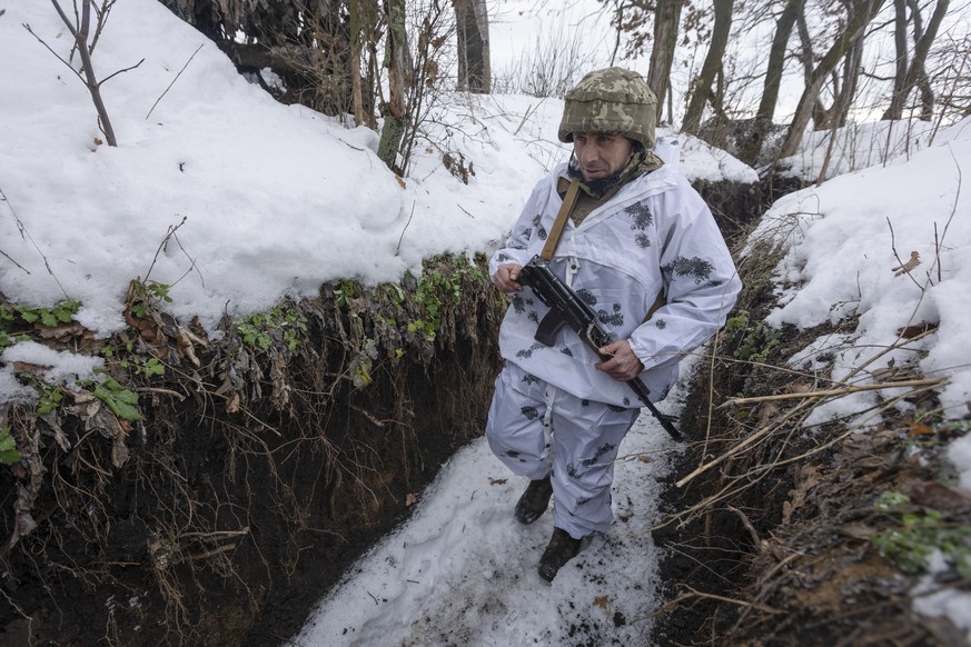 02.01.2022, Ukraine, --: Ein ukrainischer Soldat geht an der Frontlinie zu prorussischen Rebellen in der Region Donezk in einem Sch