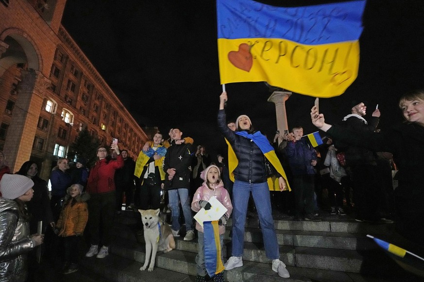 12.11.2022, Ukraine, Kiew: Menschen feiern und schwenken eine ukrainische Fahne, nachdem sie erfahren haben, dass ukrainische Truppen in die südliche Stadt Cherson, die Hauptstadt der Ende September v ...