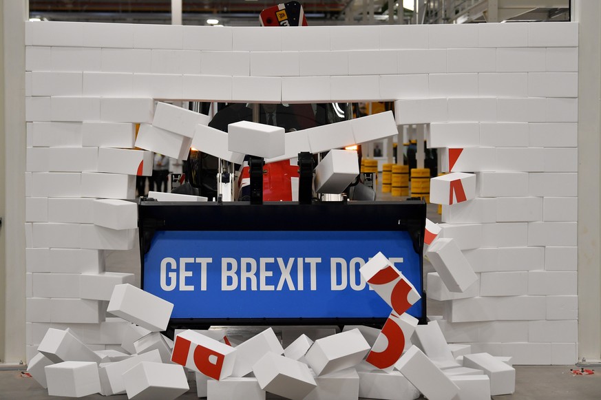 Britain's Prime Minister Boris Johnson drives a JCB machine through a symbolic wall with the Conservative Party slogan 'Get Brexit Done' in the digger bucket, during an election campaign event at the  ...