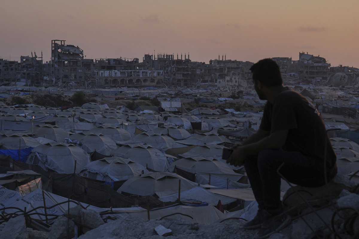 A Palestinian looks at a makeshift tent camp for people who were displaced by the Israeli air and ground operations in the Gaza Strip, as the sun sets in Gaza City, Friday, July 25, 2025. (AP Photo/Ab ...