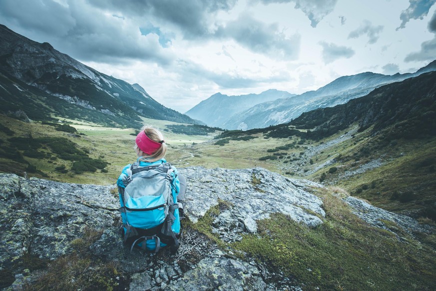 Male mountain climber with backpack is enjoying the view