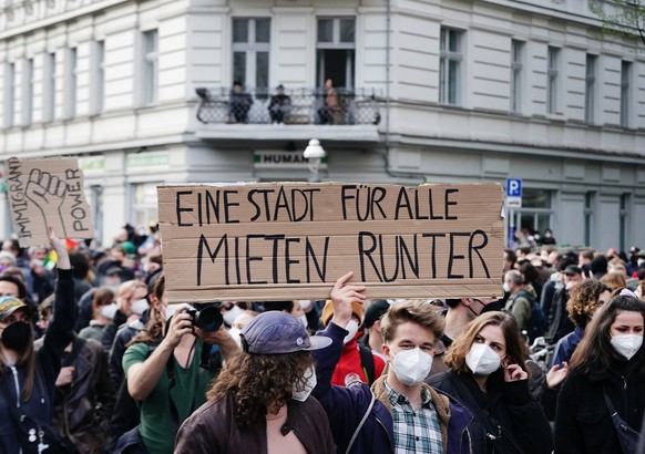 01.05.2021, Berlin: &quot;Eine Stadt f�r alle, Mieten runter&quot; steht auf dem Schild, das ein Teilnehmer beim Demonstrationszug linker und linksradikaler Gruppen unter dem Motto �Demonstration zum  ...